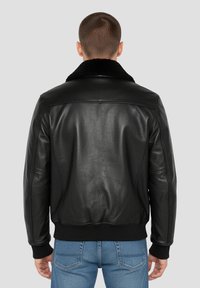 Giacca bomber in pelle nera con un morbido colletto in pelliccia nera. Presenta polsini e cintura a coste, design elegante con una texture liscia.