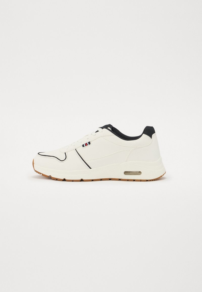 White athletic shoe with black accents, rubberized sole, and visible air cushioning. Features smooth texture and subtle design lines.