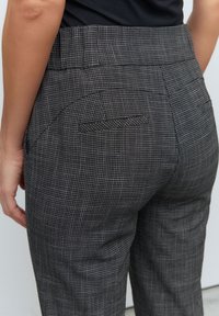 Pantaloni grigi a fantasia con un sottile motivo a scacchi, dotati di vita alta e due tasche posteriori, realizzati in tessuto testurizzato.