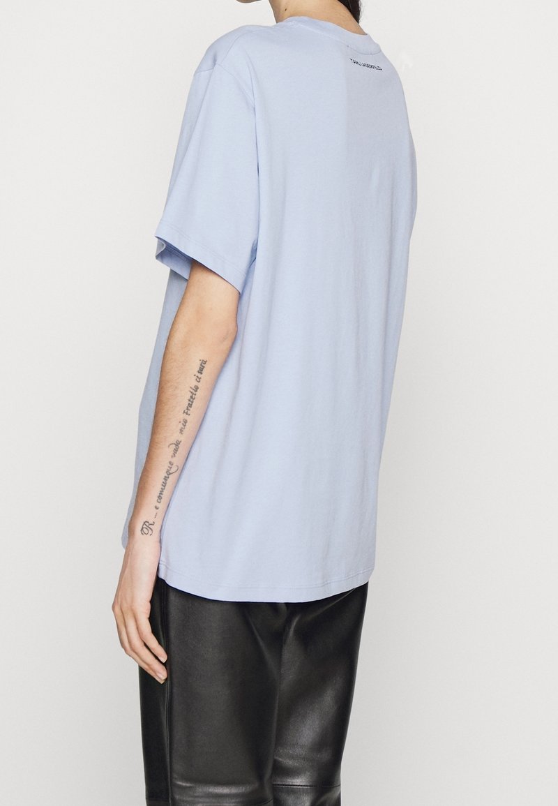 Světle modré bavlněné tričko s volným střihem, krátkými rukávy a kulatým výstřihem. Na zadní straně se nachází decentní logo a je vyrobeno z měkkého materiálu.