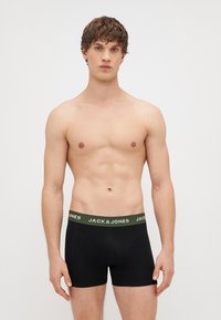Μαύρα βαμβακερά σλιπ με πράσινη ζώνη που φέρει το λογότυπο "JACK & JONES". Το ύφασμα φαίνεται λείο με εφαρμοστή σχεδίαση.