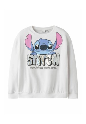 Biała bluza z dużą, kolorową grafiką postaci Stitcha, błyszczącym napisem "STITCH" oraz hasłem "bądź dobry, bądź szczęśliwy, bądź oryginalny, bądź sobą" poniżej.