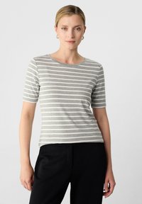 Grau-weiße gestreifte Kurzarm-T-Shirt mit rundem Ausschnitt, aus weichem Stoff, kombiniert mit schwarzen Hosen.