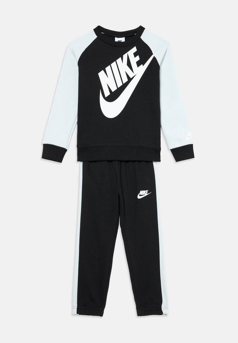 Completo da tuta Nike con una maglia nera a maniche lunghe con logo bianco e maniche azzurrine, abbinato a pantaloni neri con accenti del logo.