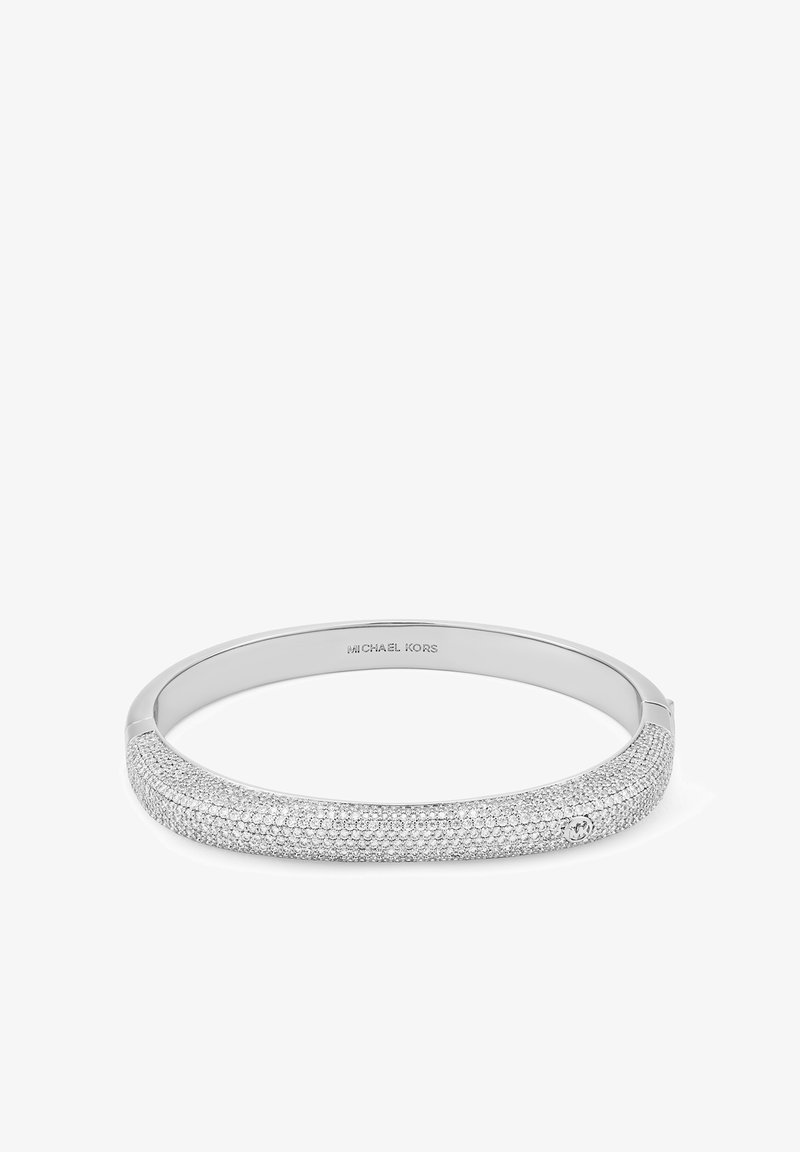 Bracelet en argent au design lisse et arrondi. Une section présente une surface texturée ornée de petites pierres étincelantes. Marqué "Michael Kors".