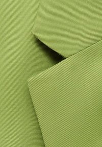 Groene textiel met een fijne ribbelstructuur, met netjes gevouwen secties die het zachte oppervlak en de uniforme kleur van het materiaal tonen.