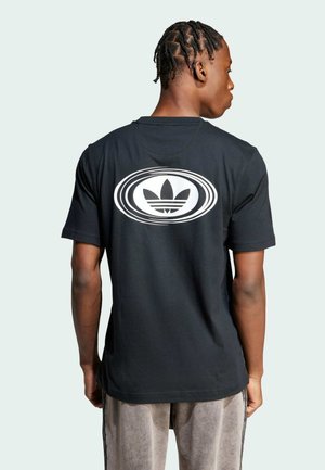 T-shirt in cotone nero con un grande logo ovale bianco con tre foglie sul retro. Maniche corte con una vestibilità rilassata.