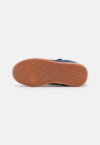 Marineblaue Sportschuhsohle mit einem strukturierten Gummimuster. Sie bietet ein flexibles Design mit kreisförmigen und linearen Profildetails.