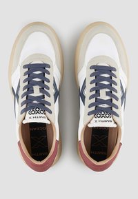 Baskets en cuir blanc avec des accents bleu marine et bordeaux, semelle intermédiaire texturée et lacets ronds. Présente un logo sur la semelle intérieure et sur le côté.