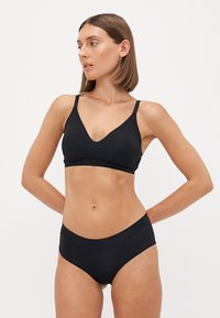Zwart bikini-set met een V-hals bralette met verstelbare banden en hooghangende slipjes, gemaakt van een soepele, rekbare stof.