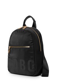 Zwarte nylon rugzak met een afgeronde vorm, voorzien van een voorvak met rits, gouden hardware en een gestructureerde schouderband. Groot logo print aan de zijkant.