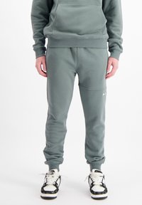 Joggeurs verts en mélange de coton doux. Présentant une taille élastique, des ourlets resserrés et des coutures contrastées. Détail de logo subtil près de la poche.