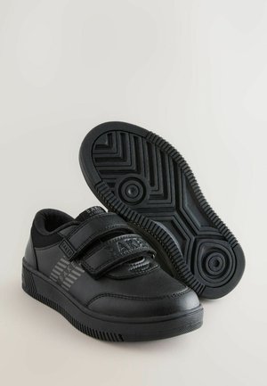 Zwarte sneakers met klittenbandsluitingen, een bovenwerk van gladleer, een gemêleerde rubberen zool met zigzagpatroon en merkbranding op de zijkant.