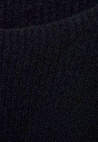 Schwarzer Strickstoff mit weicher Textur und geripptem Muster, der eine gleichmäßige dunkle Farbe und einen leichten Glanz aufweist.