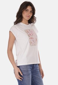 T-shirt in cotone bianco con una grafica floreale in tonalità rosa e pois, maniche corte e vestibilità morbida.