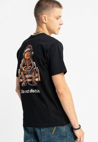 Czarny bawełniany t-shirt z kolorowym nadrukiem przedstawiającym postać piernikową noszącą słuchawki i czapkę Mikołaja, z napisem "Nie przeszkadzać."