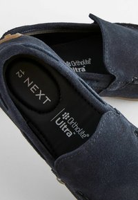 Marineblaue Wildlederschlupfschuhe mit einer weichen Textur, ausgestattet mit einer schwarzen Ortholite® Ultra-Einlegesohle und kontrastierenden Stickdetails.
