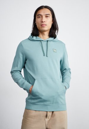 Lys teal hettegenser laget av myk stoff, med kengurulomme, snorhette og et lite logo-patch på brystet.