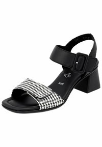 Sandali da donna con cinturino alla caviglia in pelle nera e soletta intrecciata nera e bianca. Presentano una punta quadrata e un tacco a blocco.