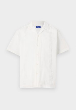 Valge lühikeste varrukatega särk nööbiga kinnituses, millel on keerukad mustrid esiosas ja klassikaline krae disain.