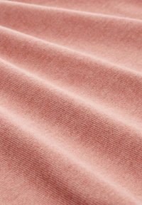 Katoenen stof met een zachte, gestructureerde oppervlakte in een gedempt roze tint, met een subtiele, egale weving en zachte plooien.