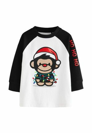 Black and white long-sleeve shirt with raglan sleeves, featuring a cartoon monkey in a Santa hat, wrapped in colorful Christmas lights.