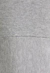 Tessuto grigio a maglia con una texture a coste, caratterizzato da due schemi di cucitura distinti e un bordo inferiore liscio.