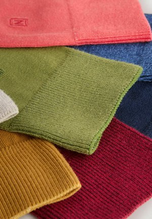 Šest vzorků pletených tkanin v různých barvách: korálová, zelená, modrá, červená, hořčicová a krémová, představujících měkké textury a žebrované vzory.