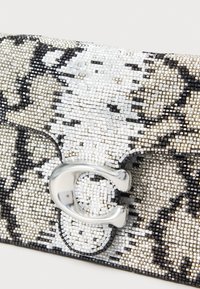 Torebka kopertówka z koralikami, z czarno-białym wzorem imitującym skórę węża, z zamknięciem na srebrne okucia i teksturowaną powierzchnią.