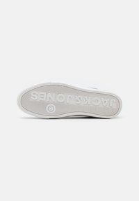 White rubber shoe sole with textured surface, circular pattern near the center, and embossed "JACK JONES" logo, providing grip and durability.
