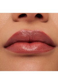 Zbliżenie na usta, z gładką teksturą, subtelnym połyskiem i przytłumionym różowo-brązowym kolorem, podkreślającym naturalne kontury i definicję.