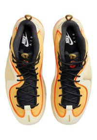 Pantofi Nike Air cu o paletă de culori galben, negru și crem. Caracteristici ale materialului texturat, șireturi negre și accente portocalii pe laturi.