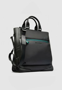 Zwarte draagtas met een gladde, matte afwerking; voorzien van een verstelbare schouderriem en een voorvak met ritssluiting met turquoise accenten voor opslag.