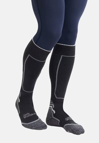 Calzini neri fino al ginocchio con accenti grigi e un motivo testurizzato. Presentano aree rinforzate per le punte e i talloni, con il marchio "Jack Wolfskin".