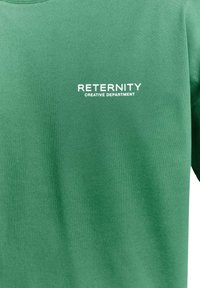 Sudadera verde hecha de una tela suave, con un logo blanco impreso que dice "DEPARTAMENTO CREATIVO RETERNITY" en la parte frontal.