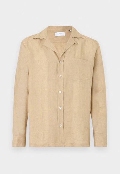 Chemise en lin beige avec un col à revers, manches longues, poche avant et fermeture à boutons. La texture est lisse et légèrement froissée.
