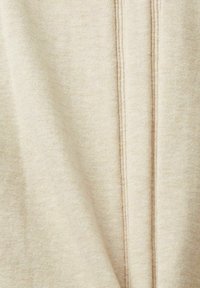 Beżowa tkanina o miękkiej teksturze, z dwoma pionowymi szwami biegnącymi wzdłuż środka. Materiał ma subtelny, melanżowy wygląd.