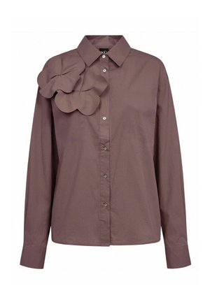 Chemise marron à manches longues, boutonnée, avec col et deux grandes applications de fleurs en tissu sur l’épaule gauche.