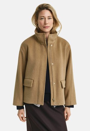 Brown wool blend jacket with a high collar, snap buttons, two front pockets, and a relaxed fit. Textured, warm, and casual design.