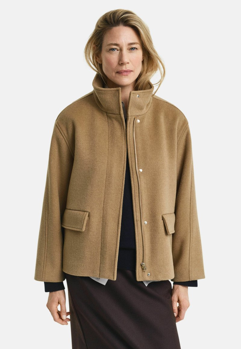 Brown wool blend jacket with a high collar, snap buttons, two front pockets, and a relaxed fit. Textured, warm, and casual design.