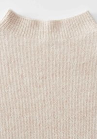 Tessuto a maglia a coste di colore crema, con una morbida e pelosa texture, che mostra la parte superiore del collo di un maglione.