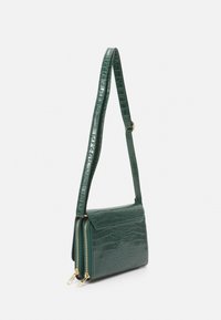Borsa a tracolla in pelle verde con stampa coccodrillo, dalla forma strutturata, dotata di due scomparti con zip e di una tracolla regolabile.