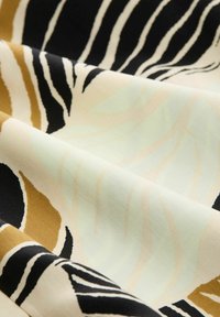 Tekstil med et mønster af sorte, hvide og beige striber på en lys mintgrøn baggrund; blød og glat tekstur.