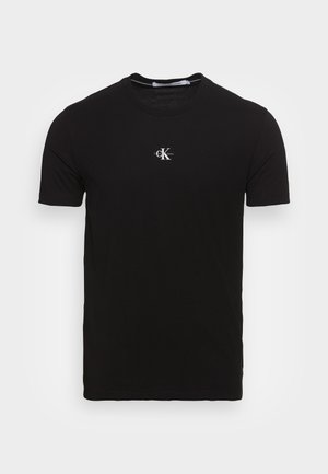 Camiseta de algodón negra con mangas cortas, escote redondo y un pequeño logo blanco en la parte superior izquierda. Textura suave, ajuste estándar.