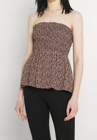 Top s peplumem bez ramínek se smocked korzetem, zdobený květinovým vzorem v purpurové, bílé a hnědé barvě, vyrobený z lehkého materiálu.