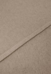 Beige gebreide stof met een gestructureerd oppervlak, voorzien van een diagonale naad. De rand heeft een schone, nette stikselafwerking.