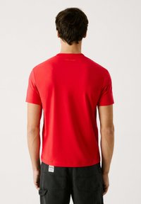 Rød T-shirt med korte ærmer og rund hals. Glat stof, enkelt design med et lille "Pepe Jeans" logo i nakken.
