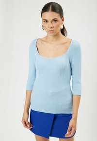 Maglia a coste di un blu chiaro, con scollatura ampia e maniche a tre quarti, caratterizzata da sottili dettagli di cuciture verticali.