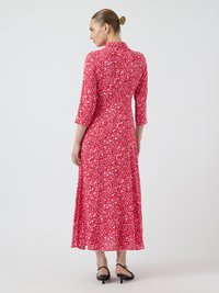 Robe maxi florale en rose vif, avec des manches 3/4 et un col. Présente une silhouette fluide et des motifs de petites fleurs élaborés.