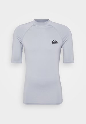 Rash guard de manga curta em cinza claro, com gola alta, textura suave e um logo preto no lado esquerdo do peito.